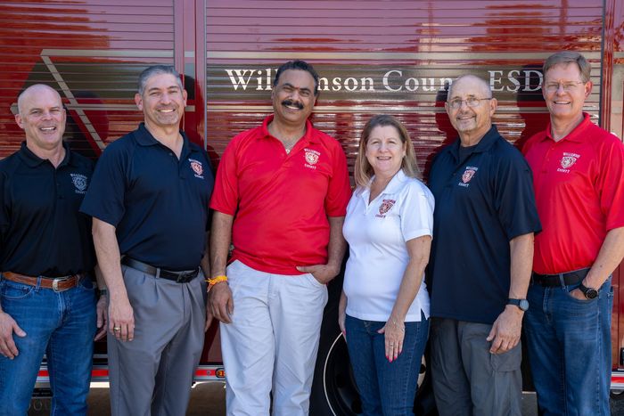 A group of people are posing for a picture in front of a fire truck.