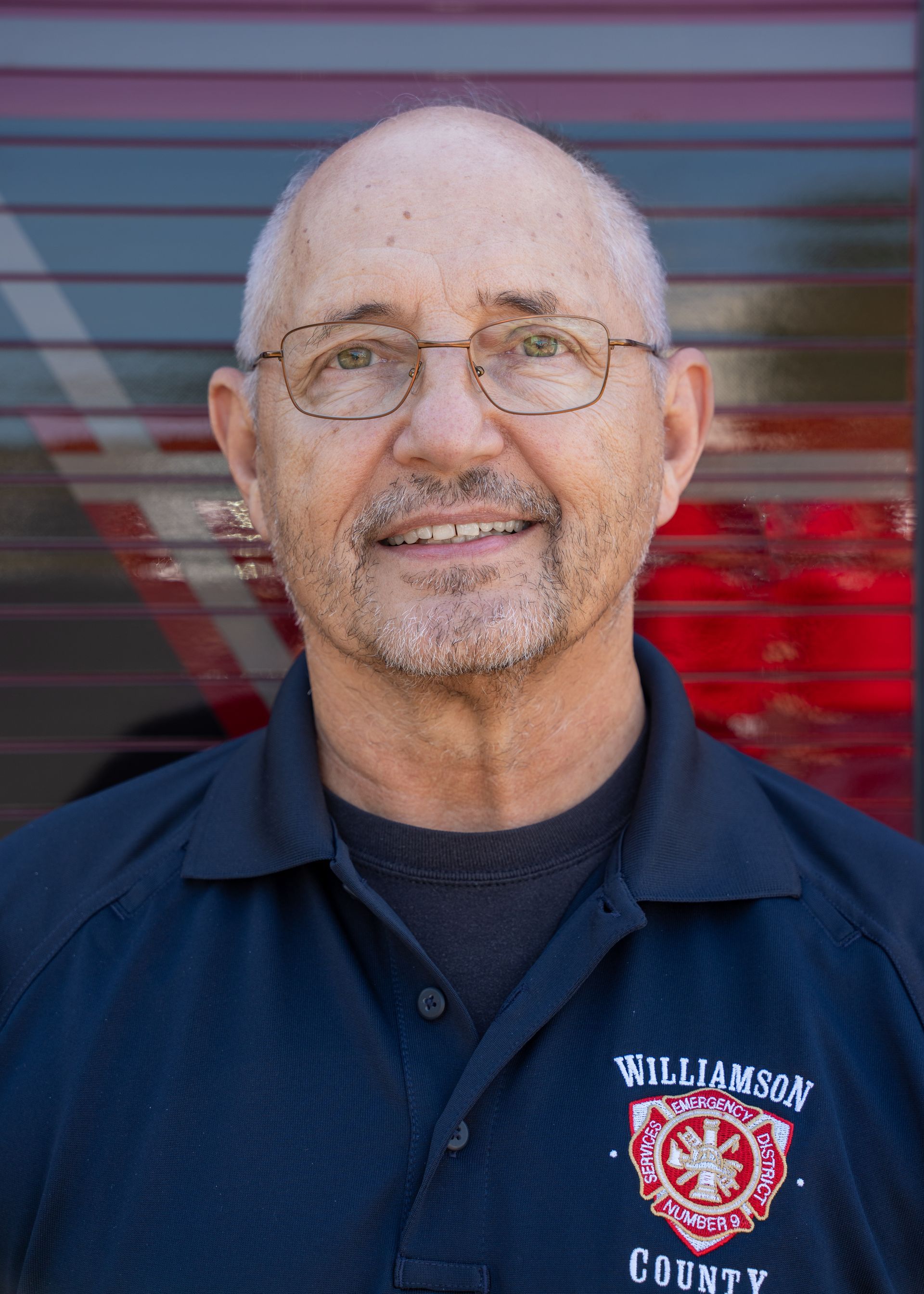 A man wearing glasses and a Williamson county shirt is smiling for the camera.