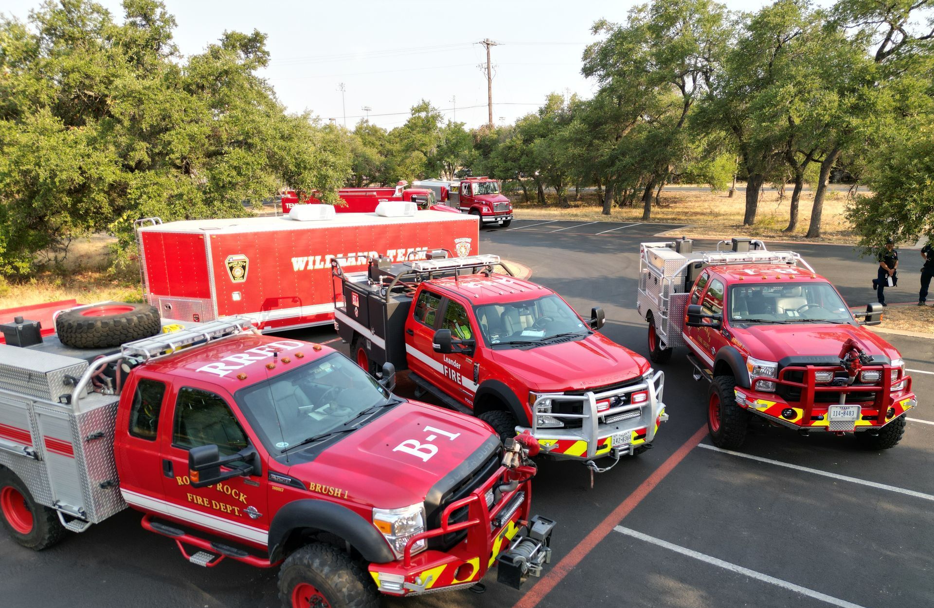 A group of red fire trucks are parked in a parking lot.