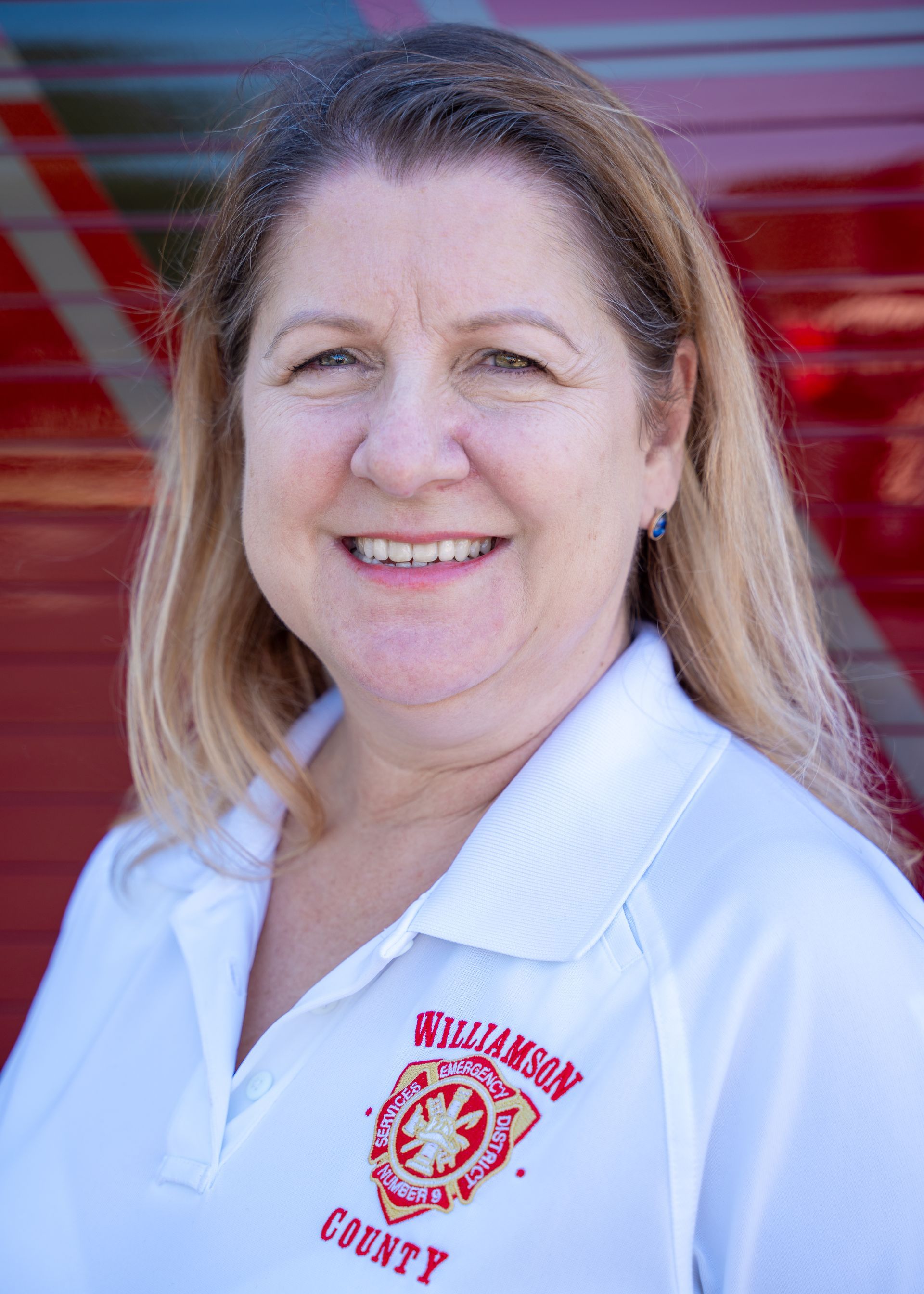 A woman in a white polo shirt is smiling for the camera.