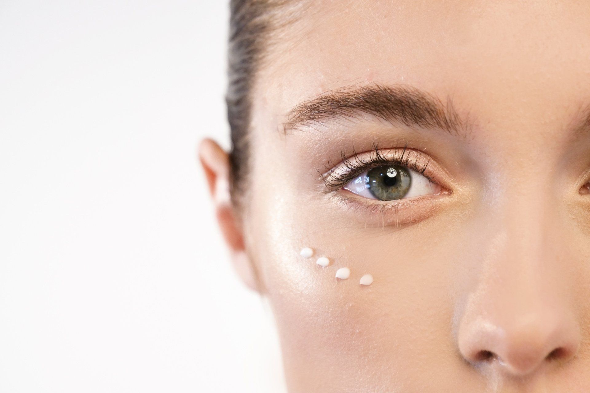 Primo piano di una donna che applica la crema per il contorno occhi.