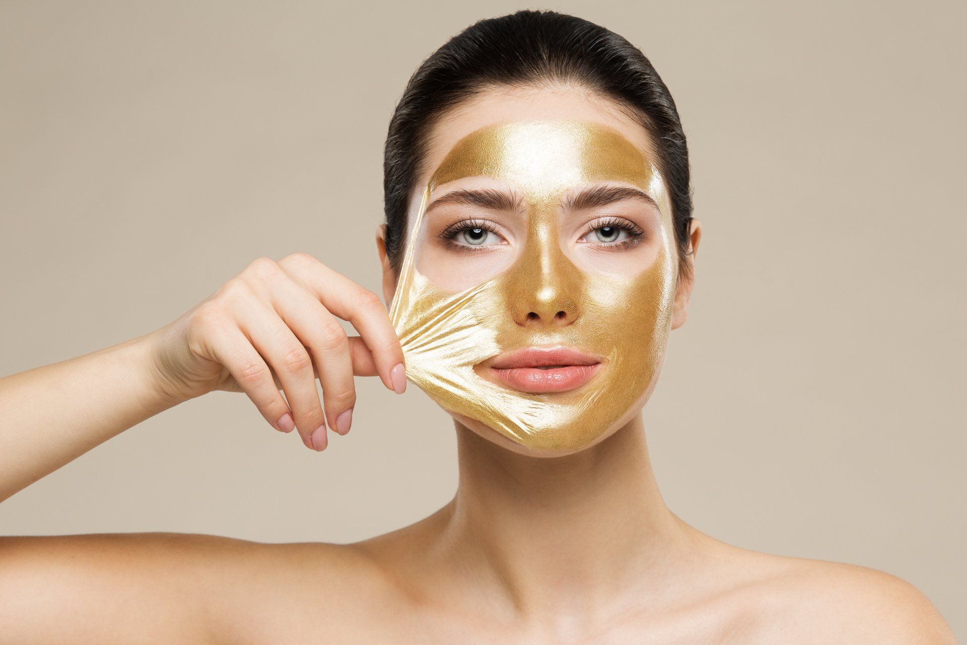 Una donna si sta togliendo una maschera d'oro dal viso.