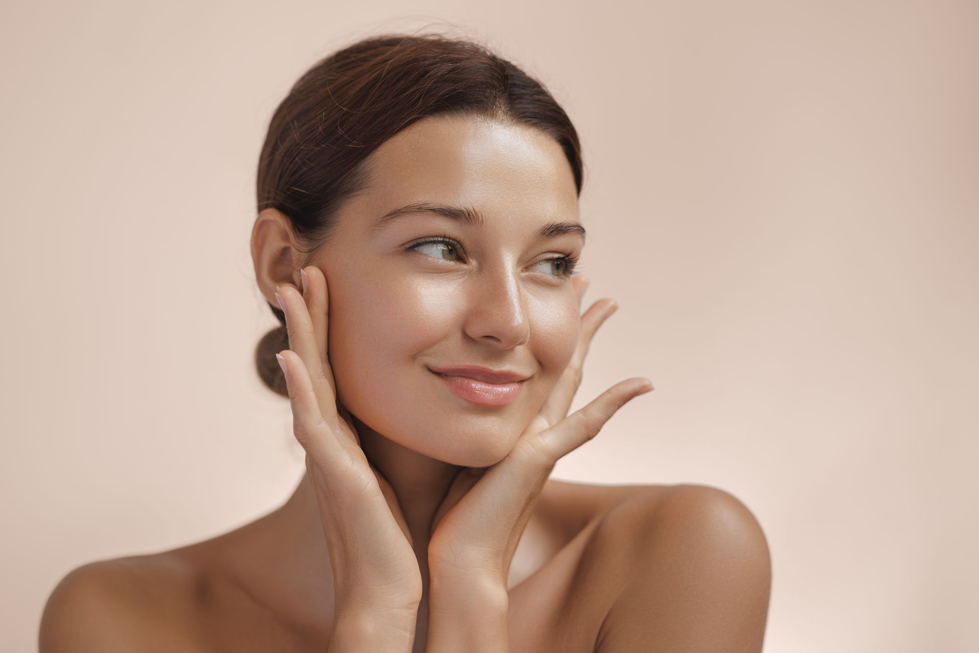 Una donna si tocca il viso con le mani e sorride.