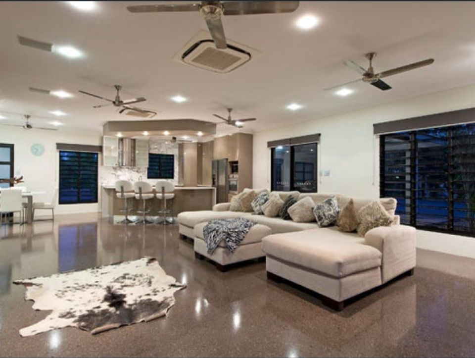 Open-concept living space with beige sectional sofa, polished floor, kitchen in the background, ceiling fans — AKW Builders Pty Ltd In Leanyer, NT