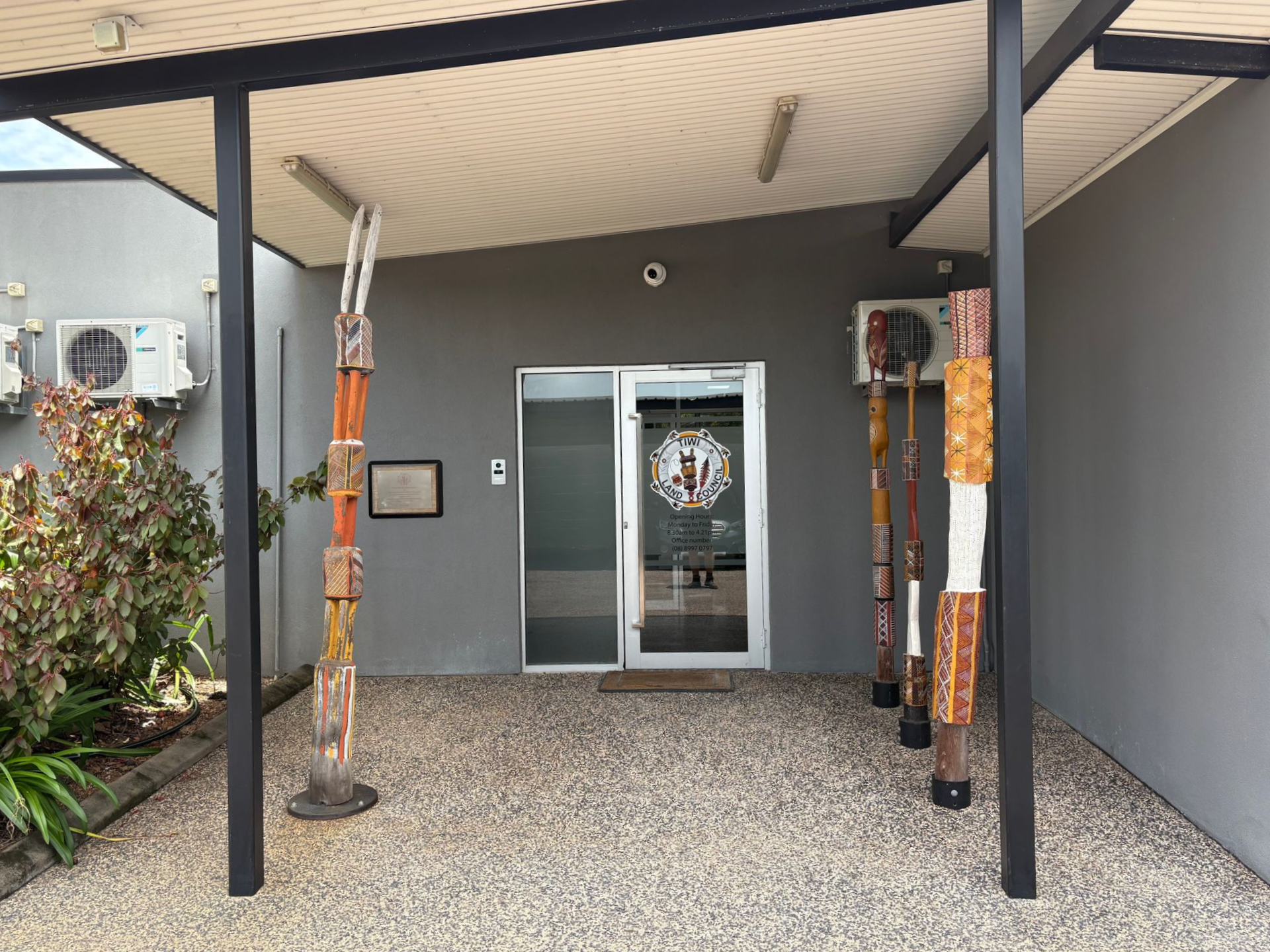 Entrance to a building with a covered walkway, glass door, and decorative poles. Gravel ground — AKW Builders Pty Ltd In Leanyer, NT