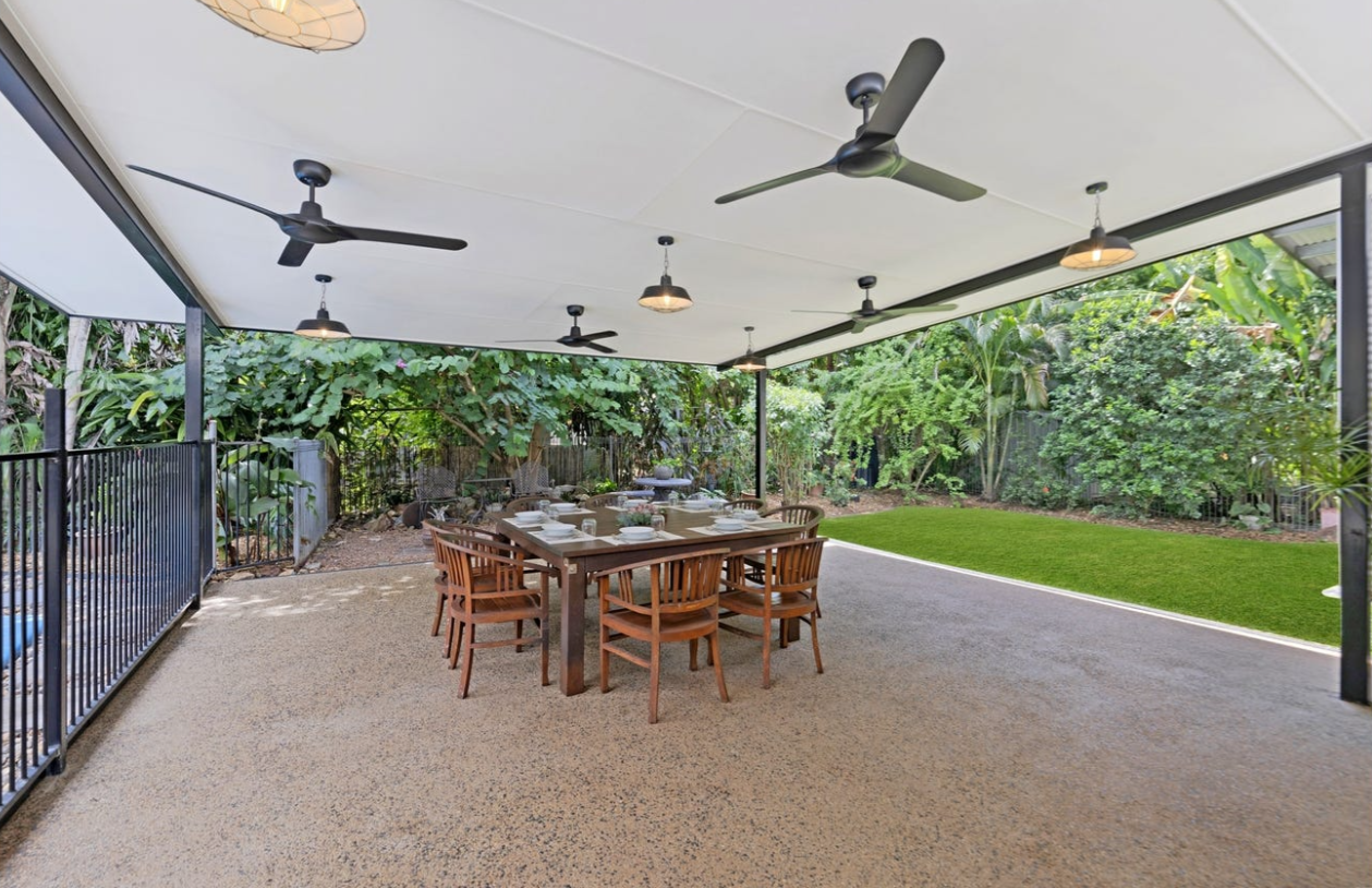 Covered patio with dining table, chairs, fans, and lush greenery in the background — AKW Builders Pty Ltd In Leanyer, NT