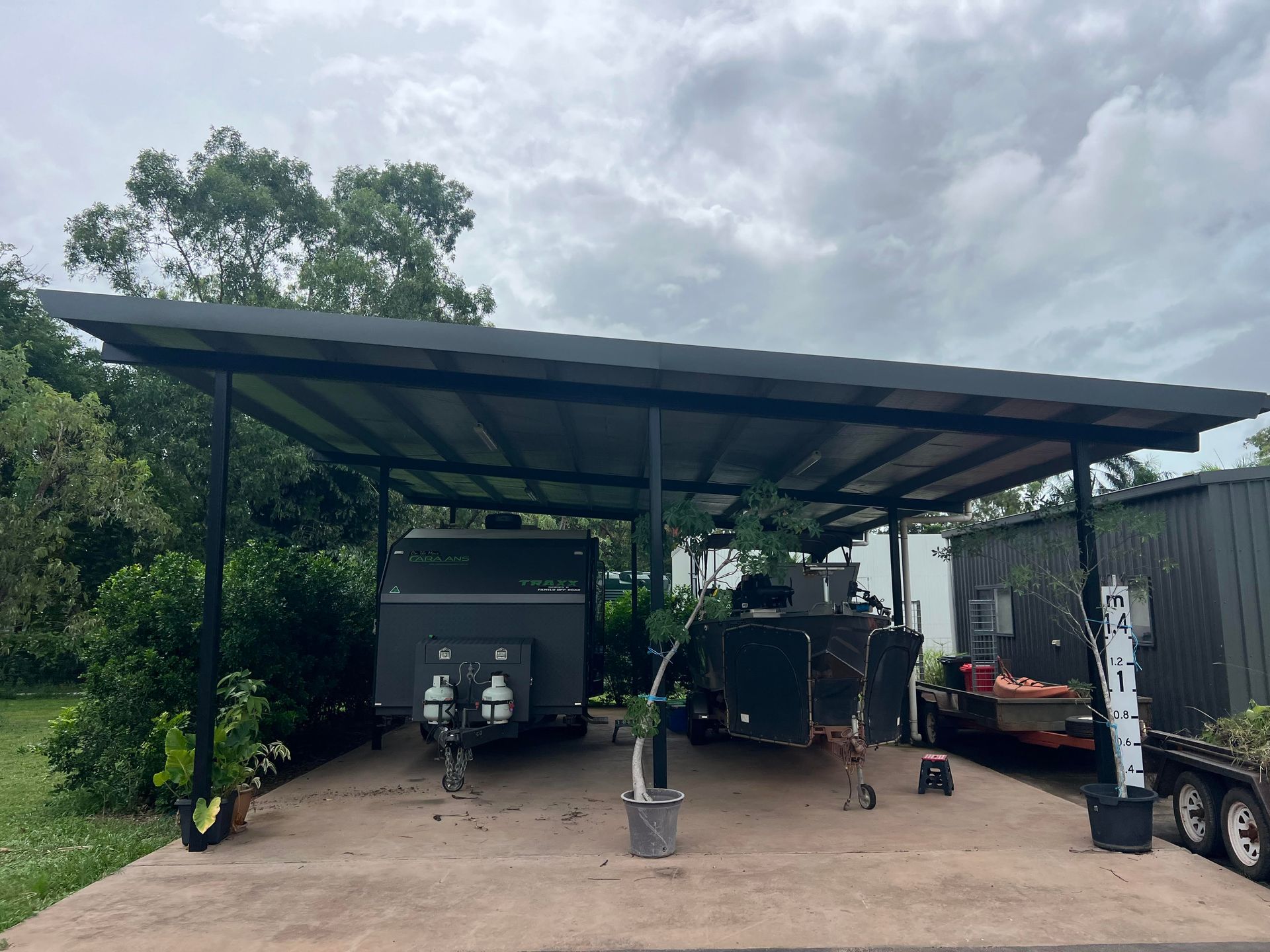A covered carport sheltering two trailers parked on a concrete slab; overcast sky — AKW Builders Pty Ltd In Leanyer, NT