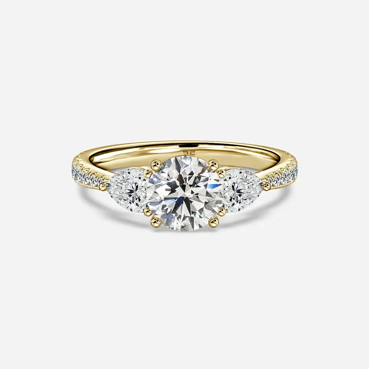 Gold ring with three diamonds: one round center stone and two pear-shaped side stones, with pavé diamonds on the band.
