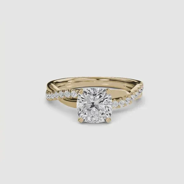 Yellow gold ring with a cushion-cut diamond center stone and twisted, diamond-paved band.