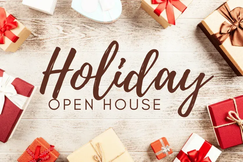A wooden table topped with gifts and the words `` holiday open house ''.