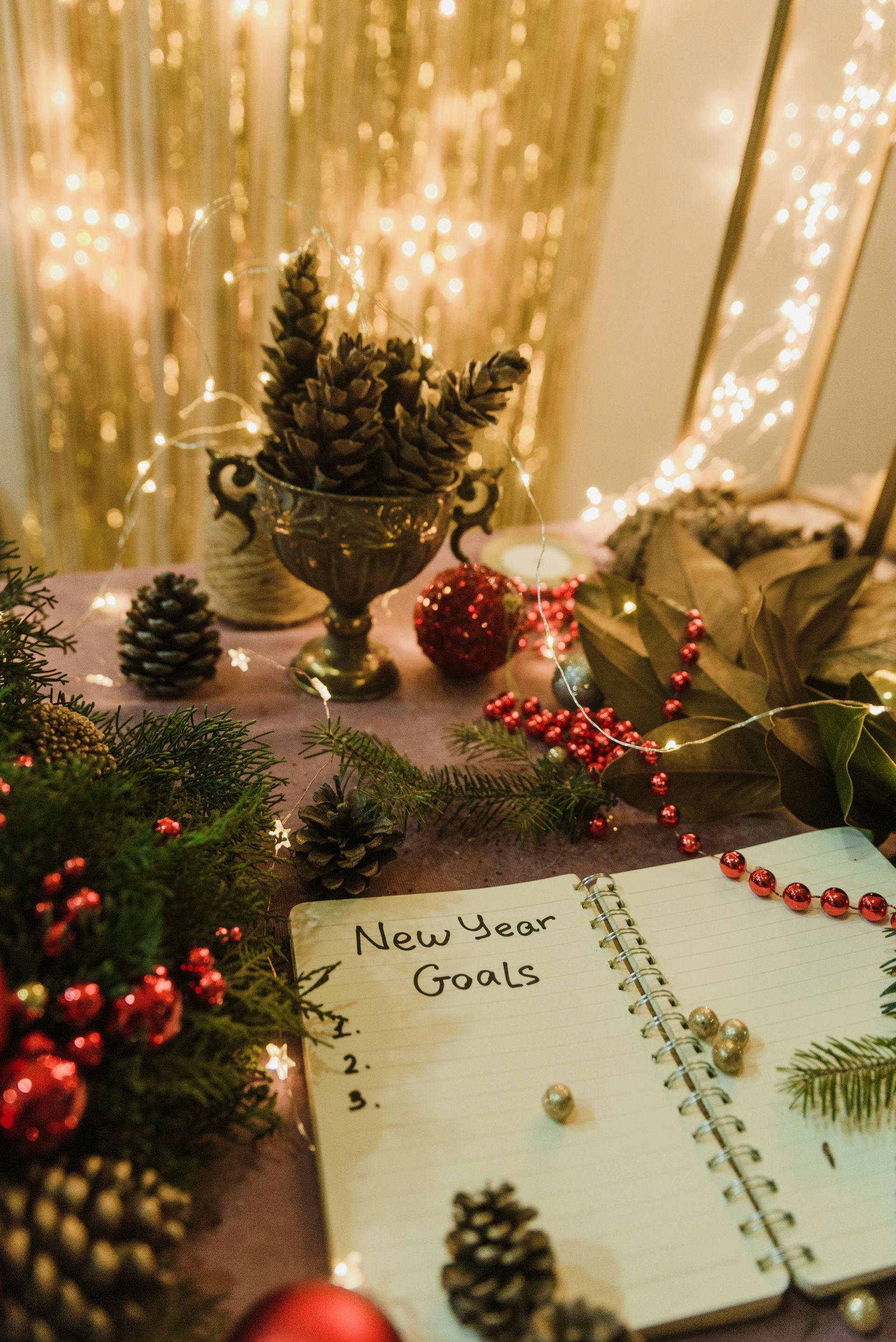 A notebook with new year goals written on it is sitting on a table surrounded by christmas decorations.