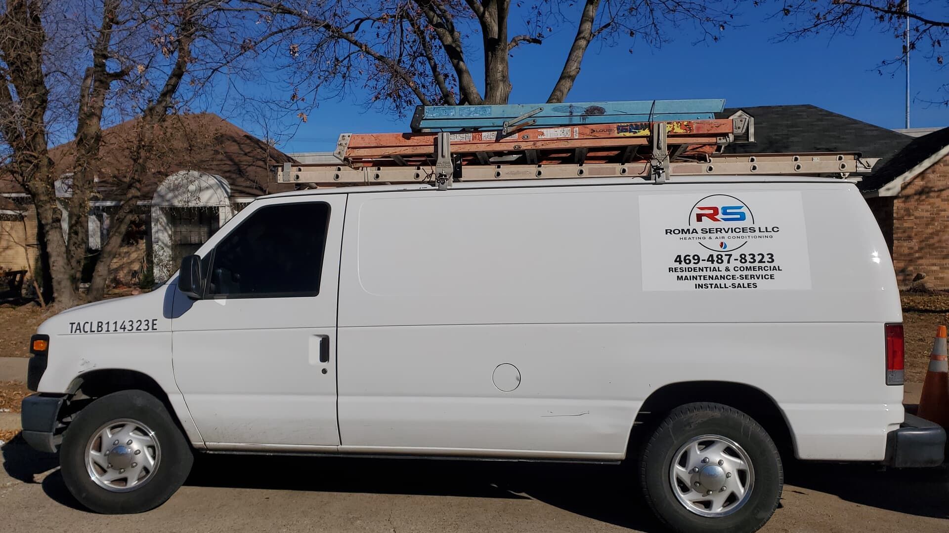 A white work van with a ladder rack on top and a company logo on the side, parked outdoors on a sunny day.