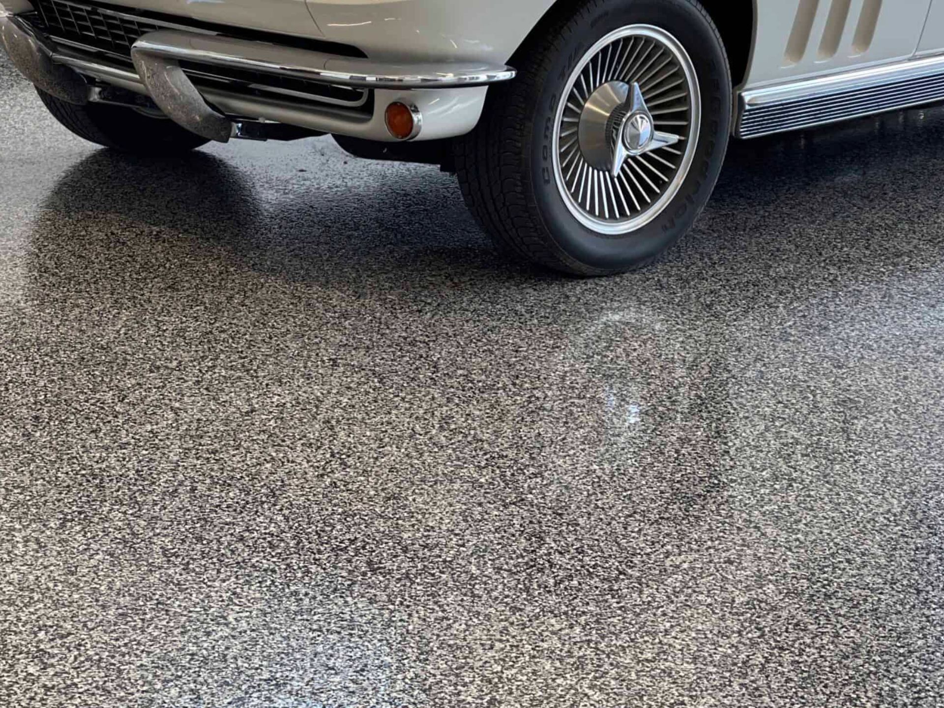A white car is parked in a garage with a gray floor.