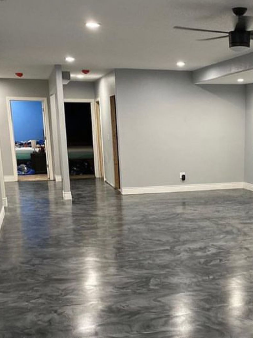 A living room with a ceiling fan and a gray floor.