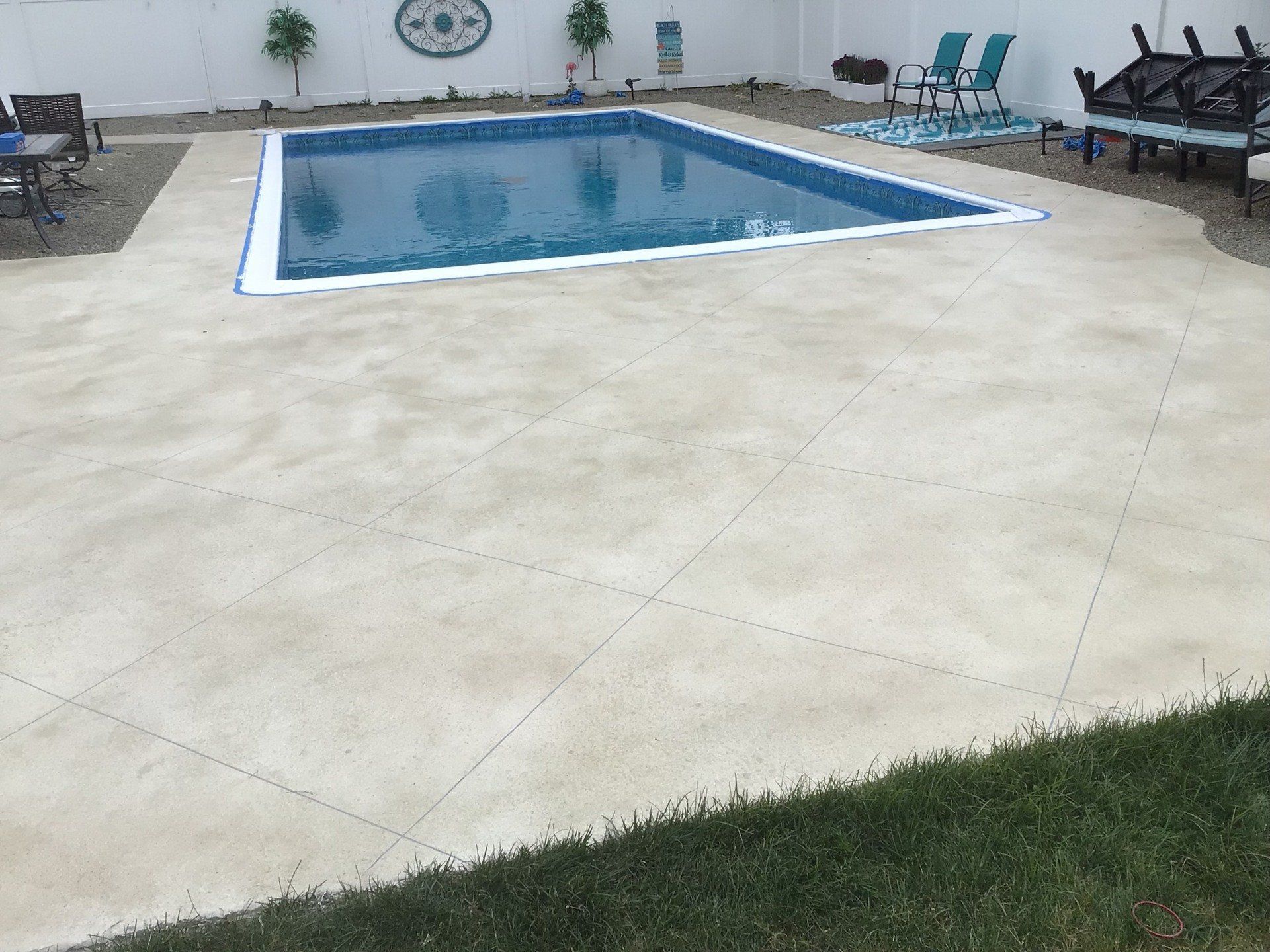 A large swimming pool is surrounded by chairs and tables