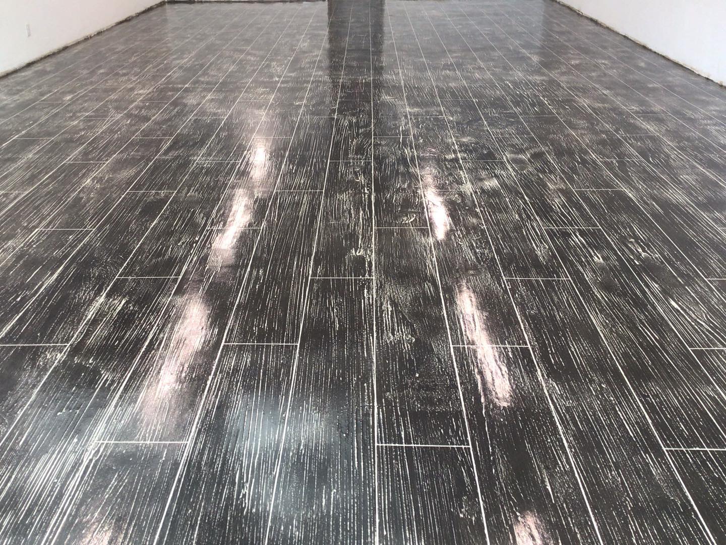 A room with a black wooden floor and white walls.