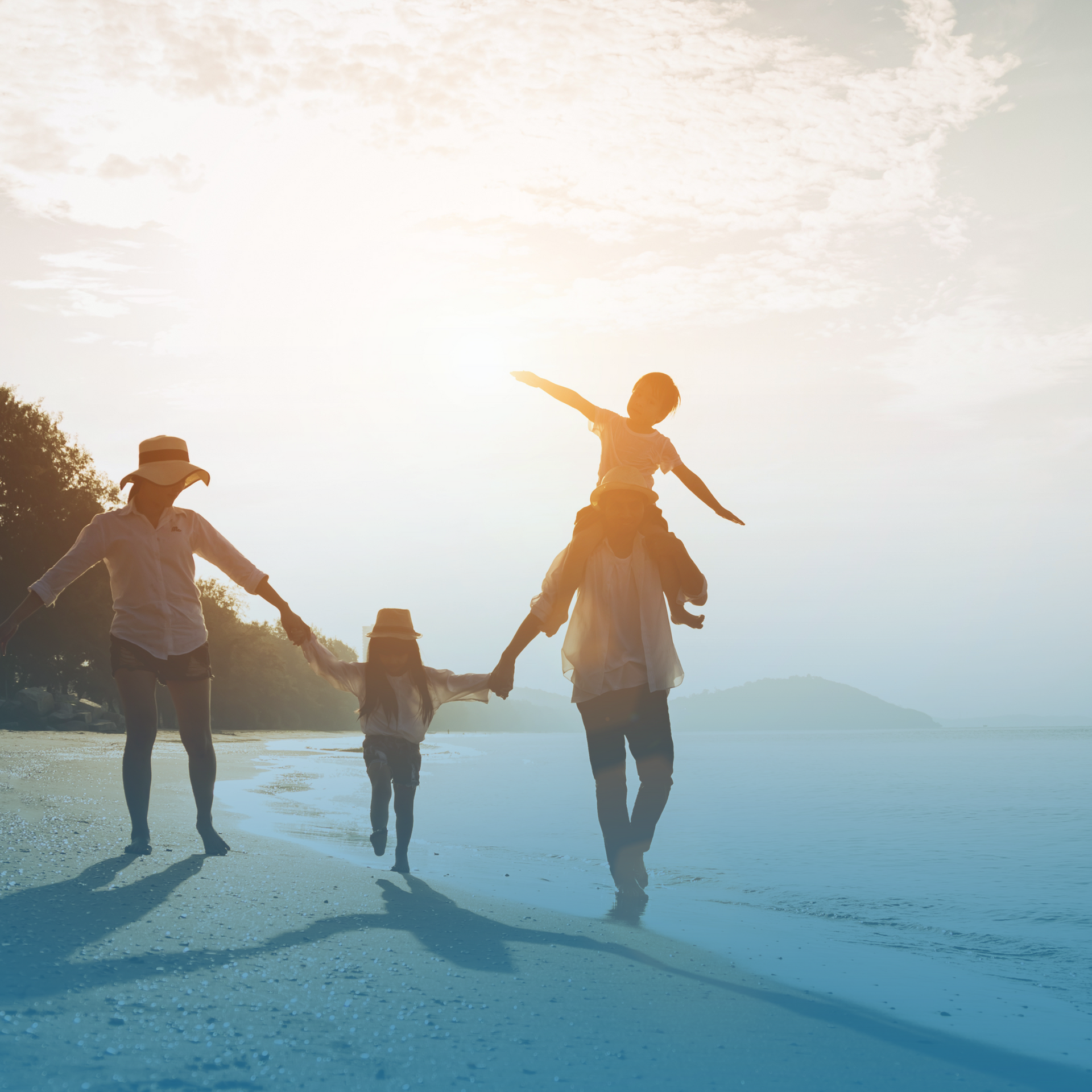 Four people holding hands and playing on a sunlit beach at sunset