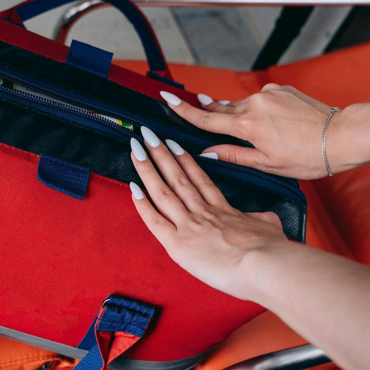 A woman is putting something in a red bag.