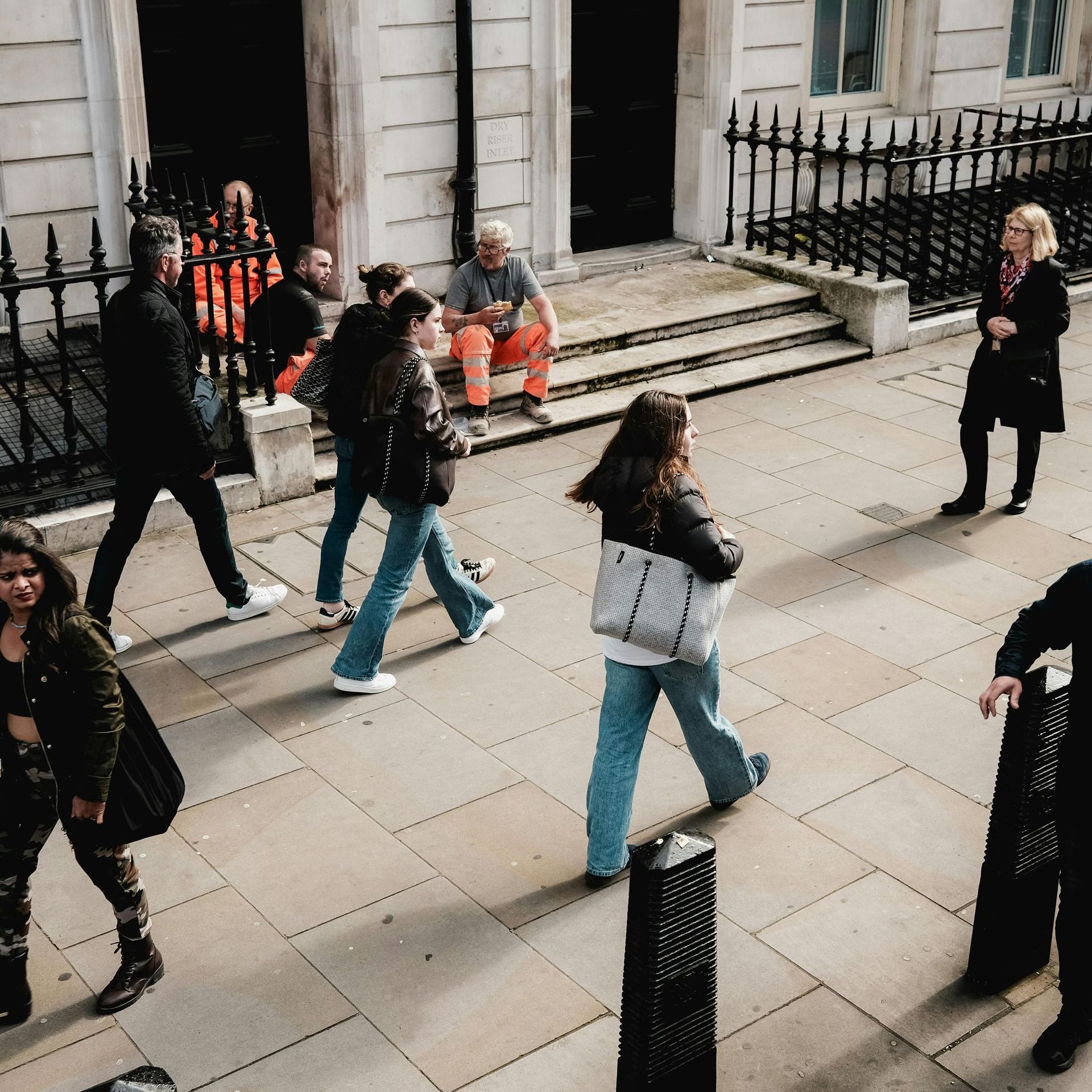 A group of people are walking down a sidewalk in front of a building