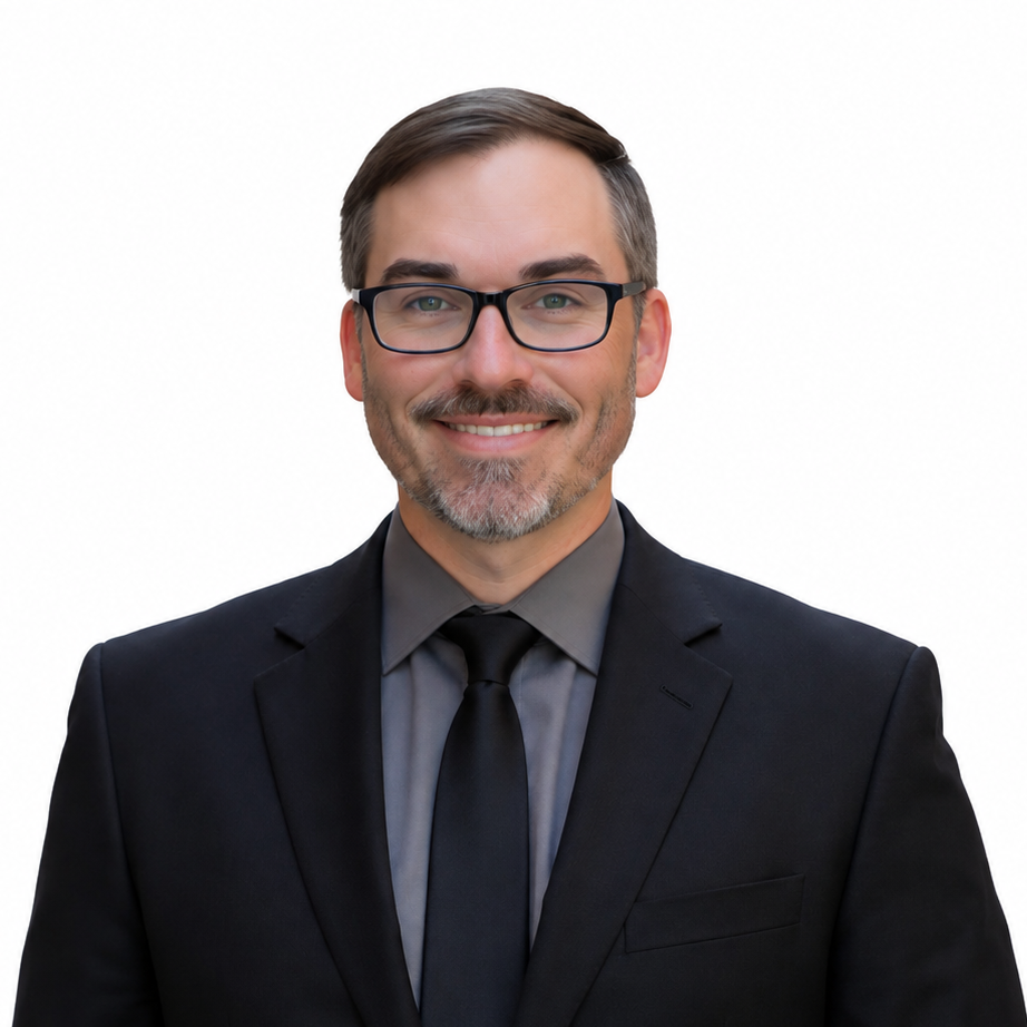 Portrait of a smiling man in a black suit, gray shirt, and tie against a white background