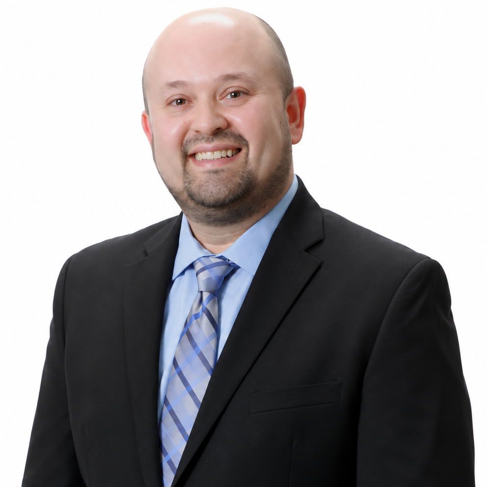 Smiling man in a black suit, light blue shirt, and striped tie against a white background