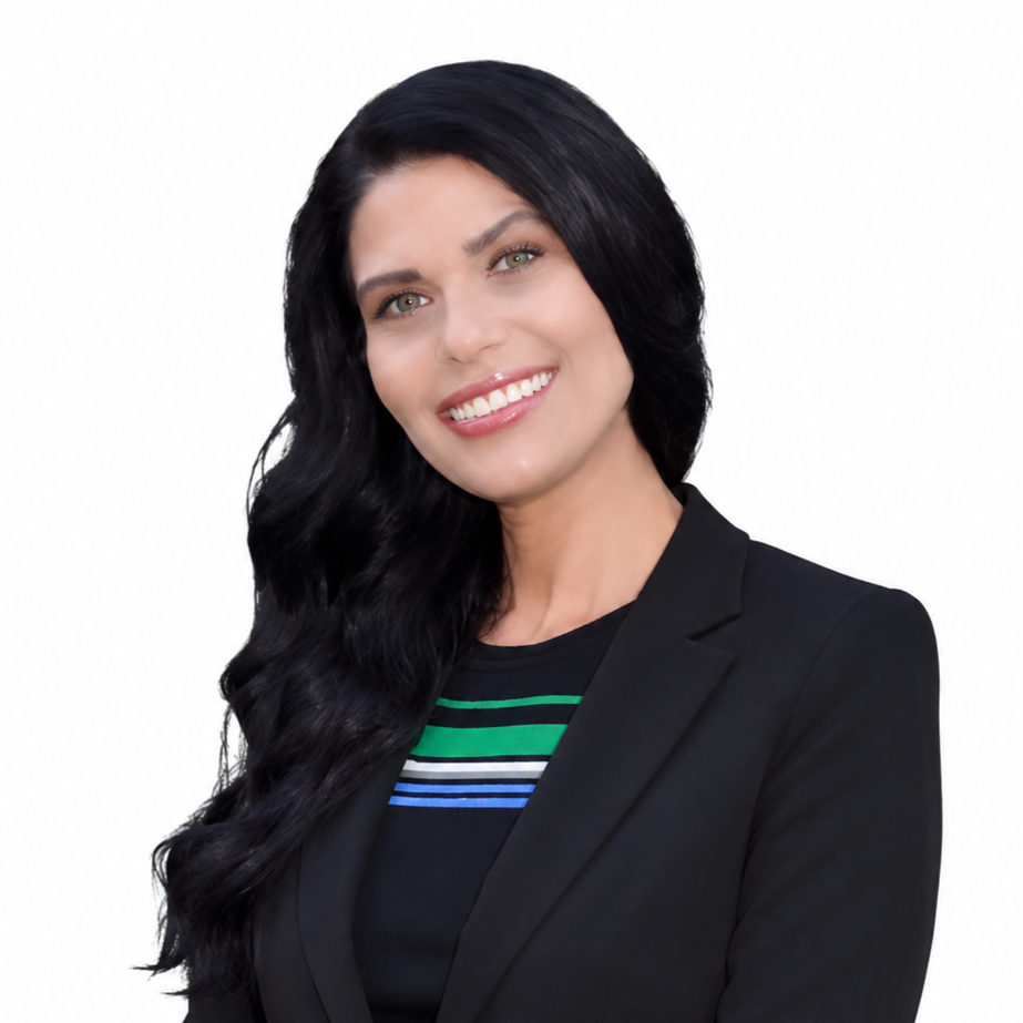 Smiling person with long black hair wearing a black blazer and striped top on a white background