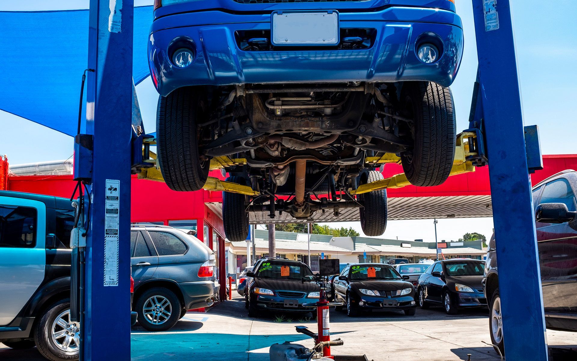 A blue truck is being lifted on a lift at a car dealership.
