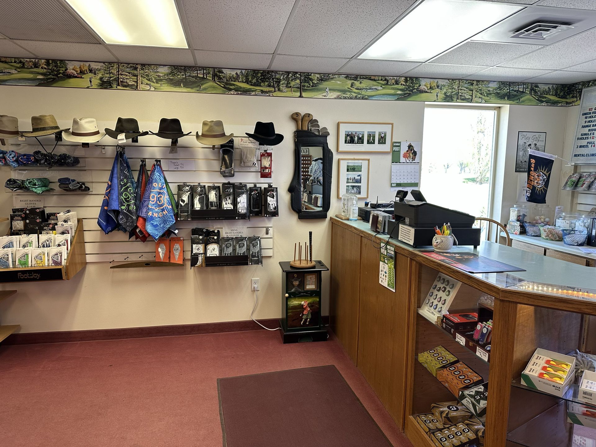 Small retail shop interior with shelves of hats, bags, and souvenirs, plus a wooden counter by a bright window.