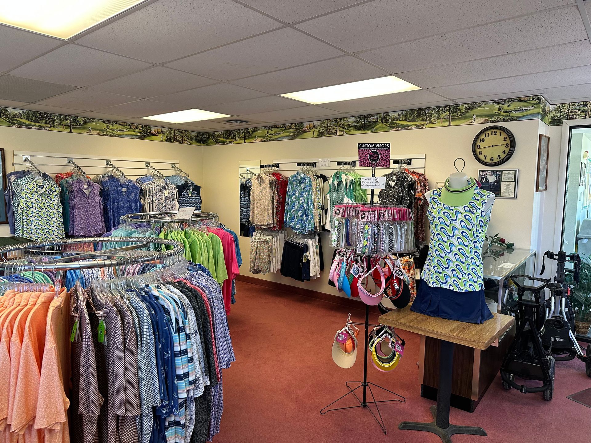 Clothing store interior with racks of colorful clothes, mannequins, and a wooden table display.