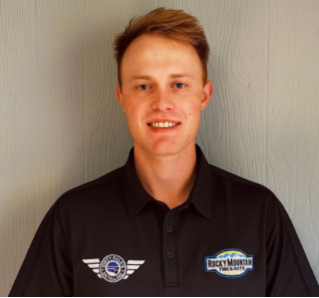 Man wearing black shirt with logos, smiling, in front of a light-colored wall.  | Rocky Mountain Car Care