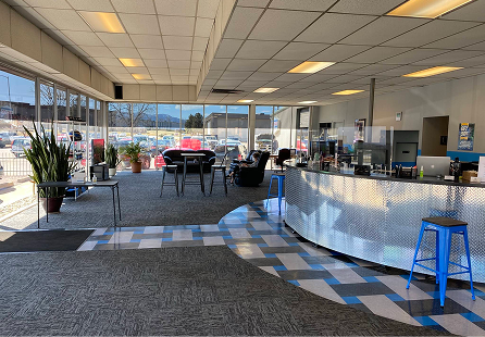 Interior of a car dealership, with a seating area, front desk, and view of cars outside. | Rocky Mountain Car Care