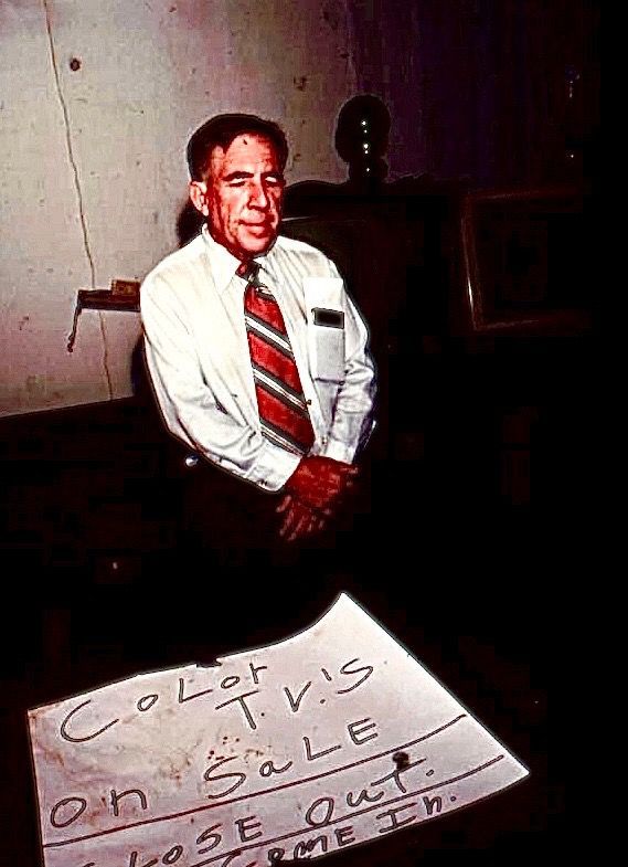 A man sits near a sign that reads 