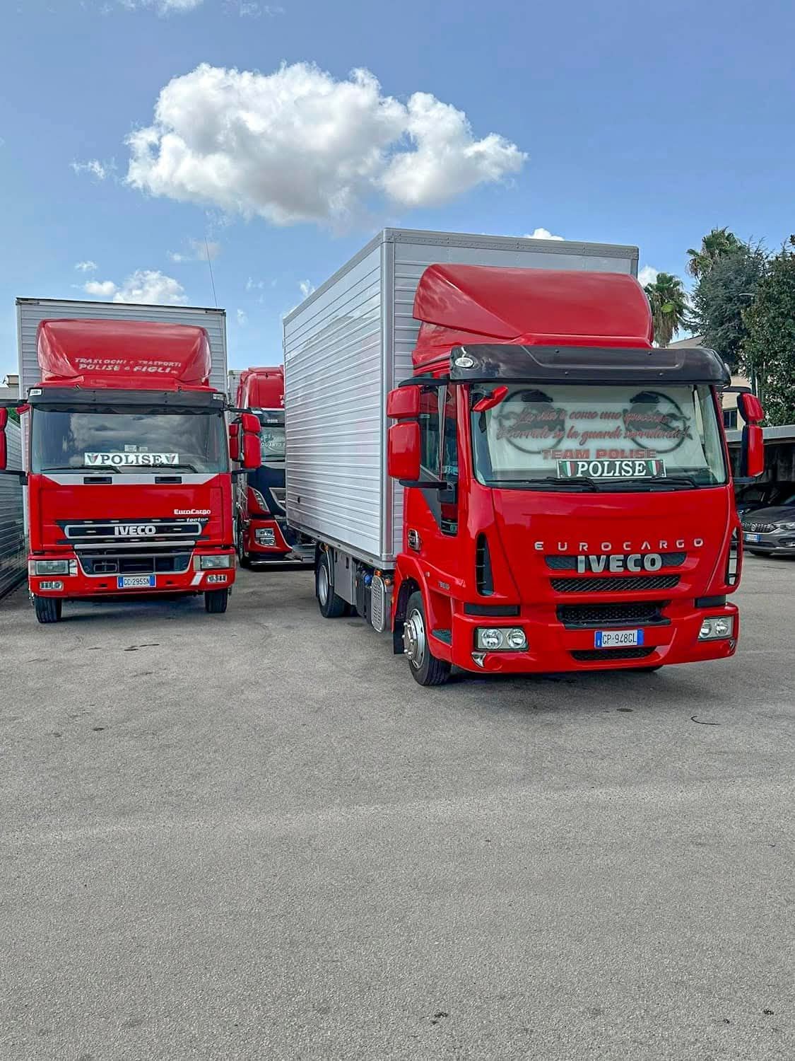 Due furgoni Iveco rossi parcheggiati fianco a fianco in un piazzale sotto un cielo parzialmente nuvoloso.