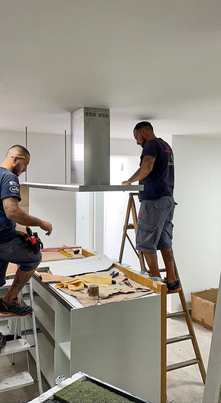 Due operai installano un pannello a soffitto in una luminosa cucina in fase di ristrutturazione.