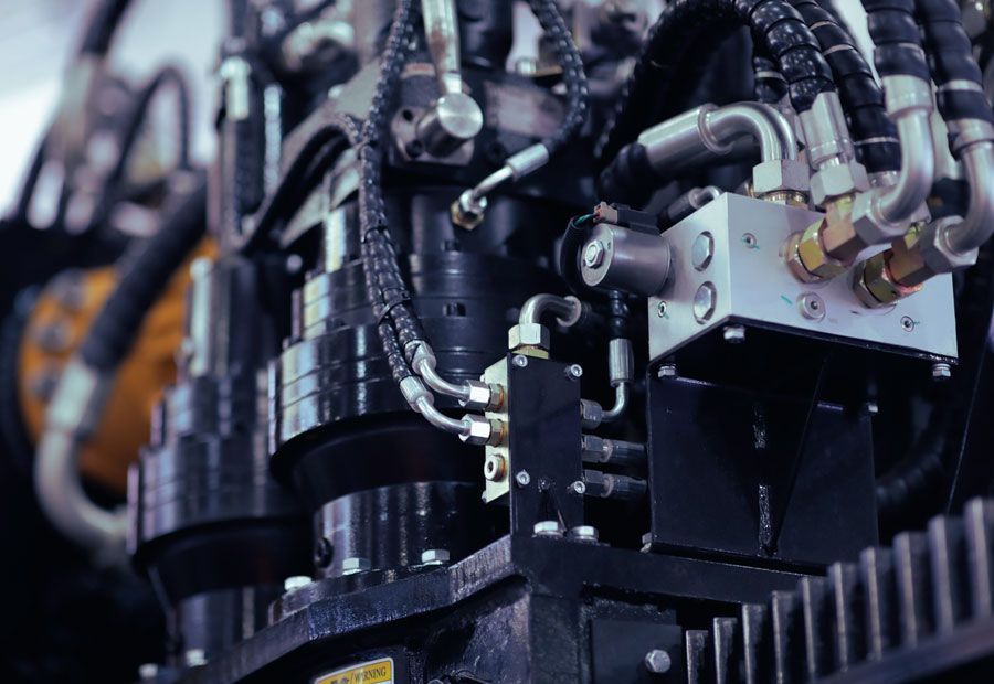 Close-up of industrial hydraulic machinery with black metal components and hydraulic lines.