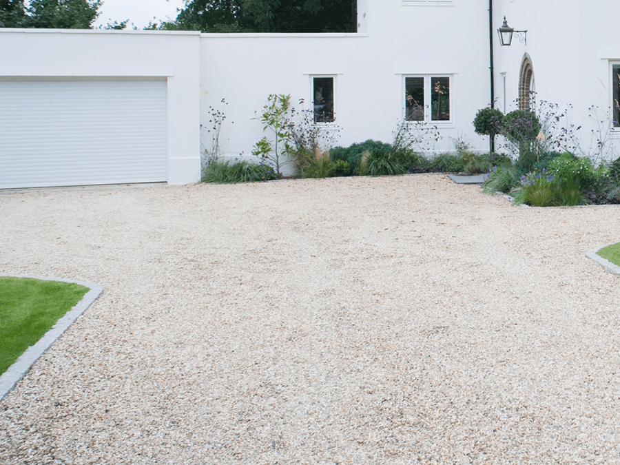 A white house with a gravel driveway in front of it