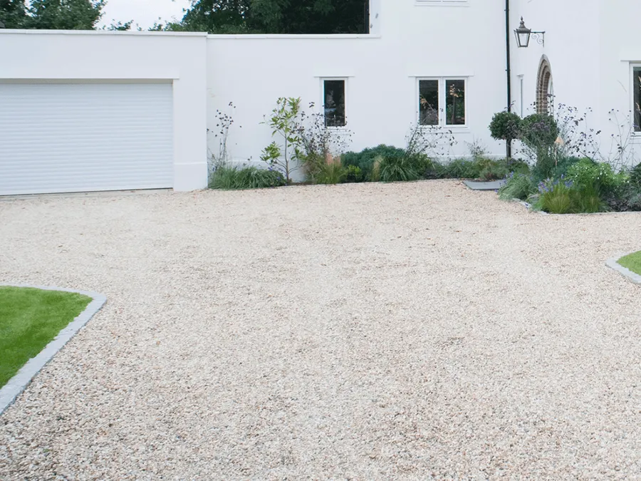 A white house with a gravel driveway in front of it