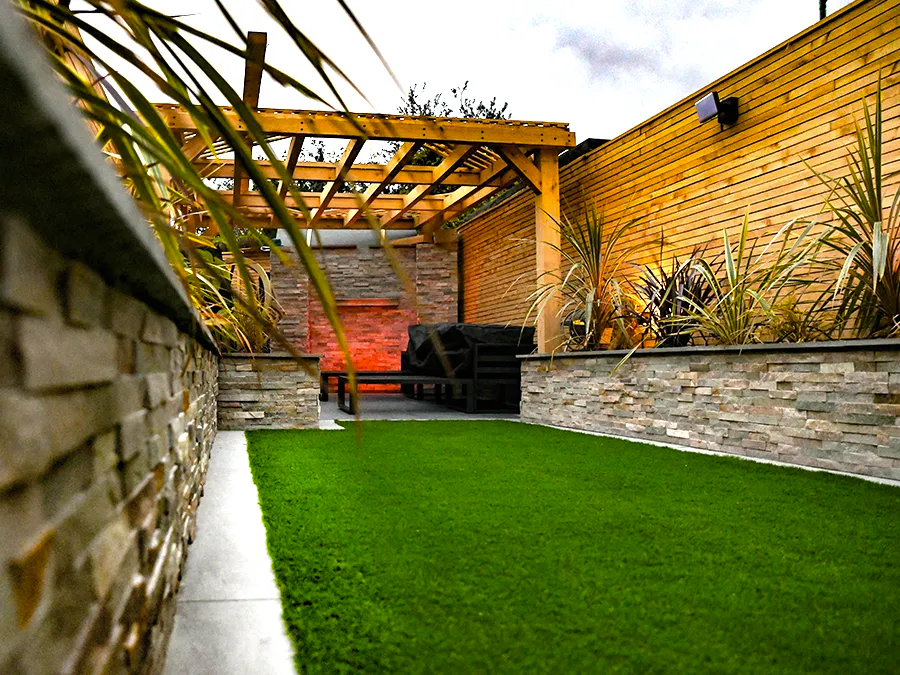 A garden with a pergola and a brick wall