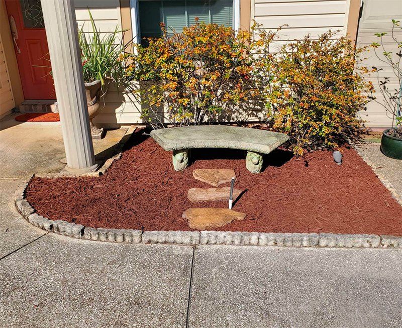 A stone bench is sitting in a garden in front of a house.