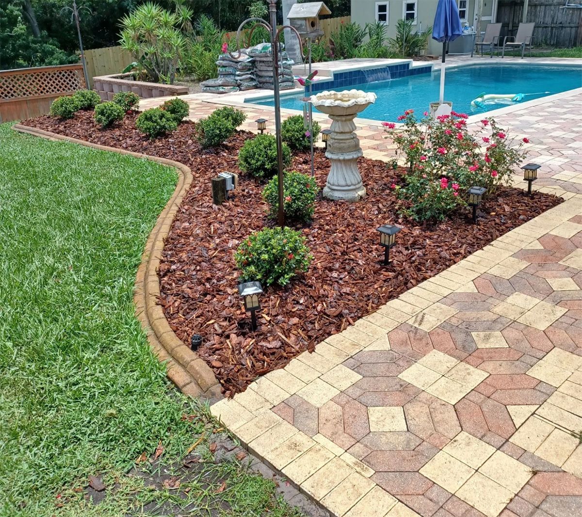 A brick walkway leading to a swimming pool in a backyard.