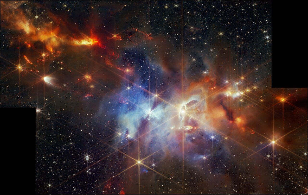 Vibrant cosmic nebula, blues, reds, and oranges, with numerous bright stars scattered throughout.