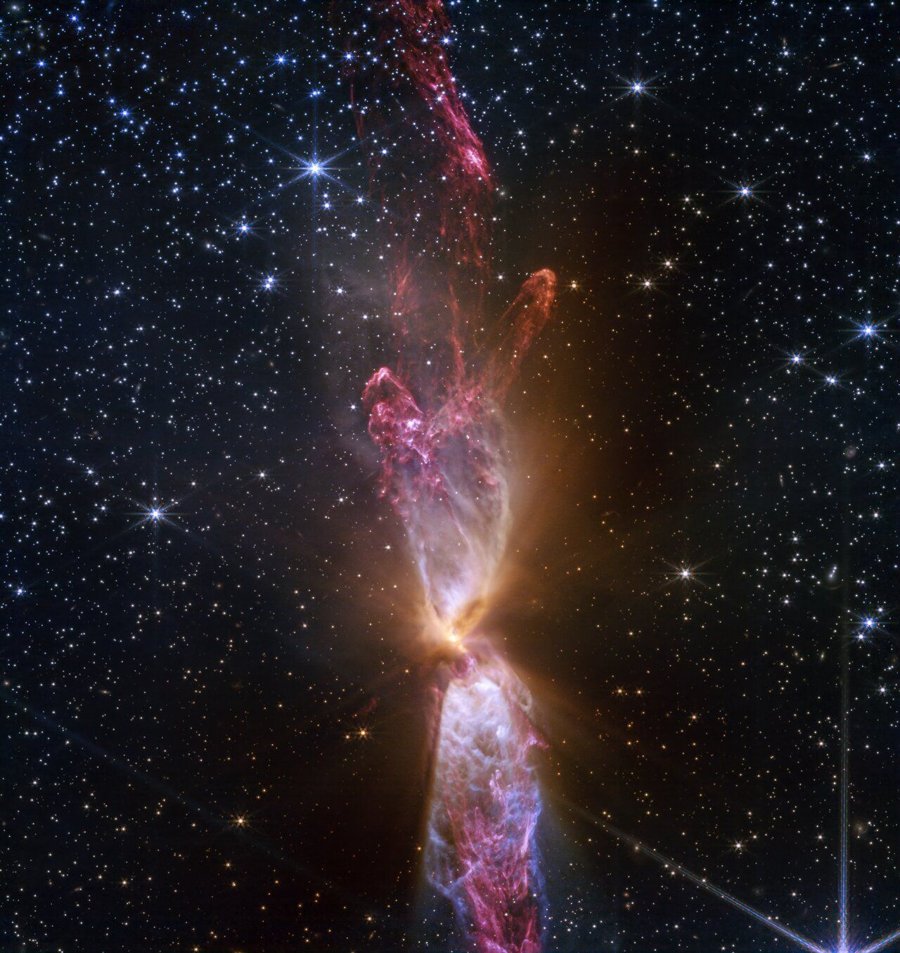 Vivid space nebula with elongated, glowing clouds of gas and dust, amidst a field of stars.