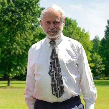 A man in a white shirt and tie is standing in a park
