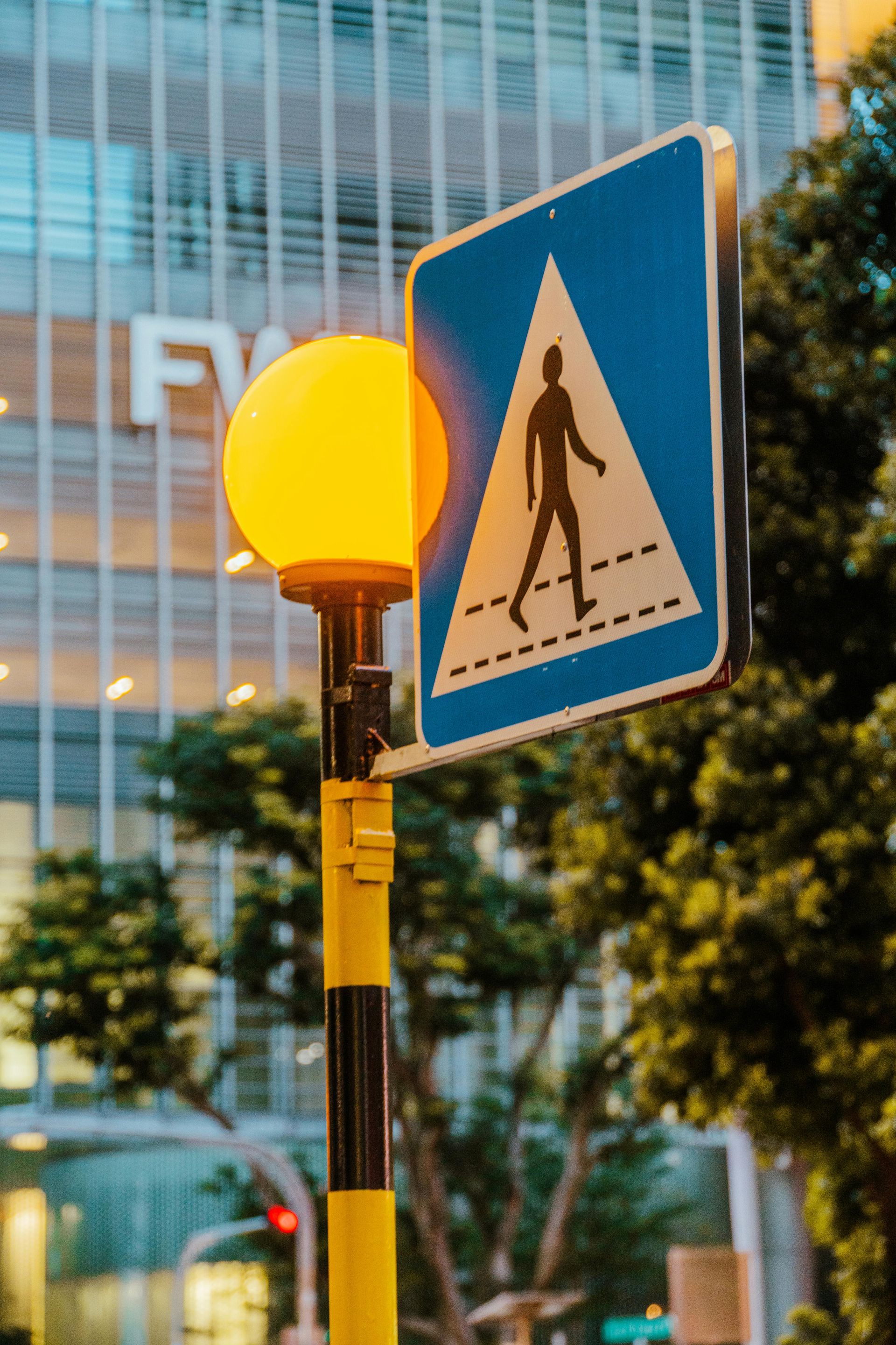 A pedestrian crossing sign is hanging from a street light.