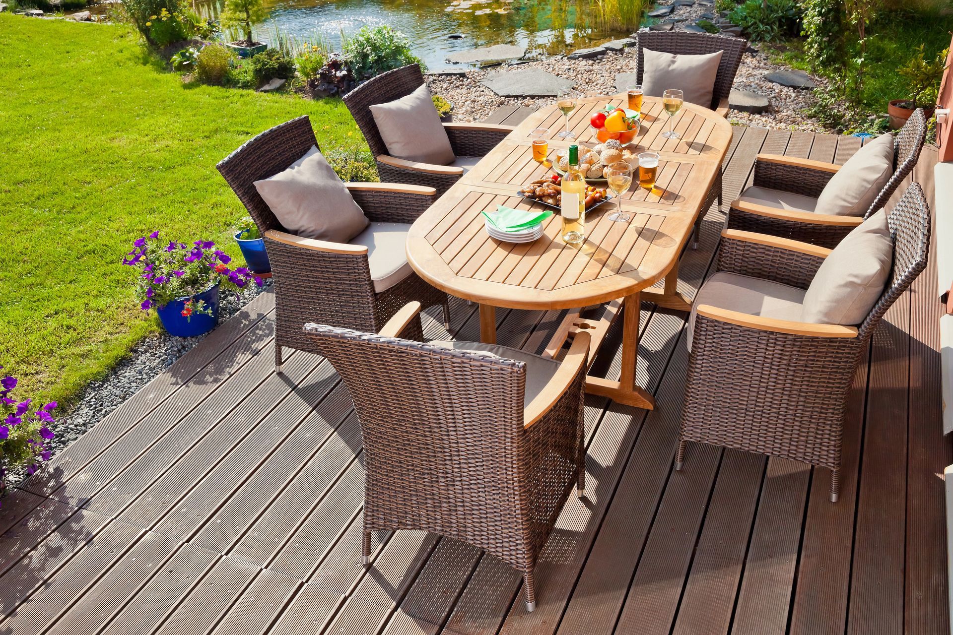 Sala da pranzo all'aperto su una terrazza in legno vicino a uno stagno.