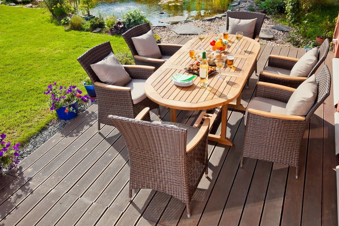Sala da pranzo all'aperto su una terrazza in legno vicino a uno stagno.