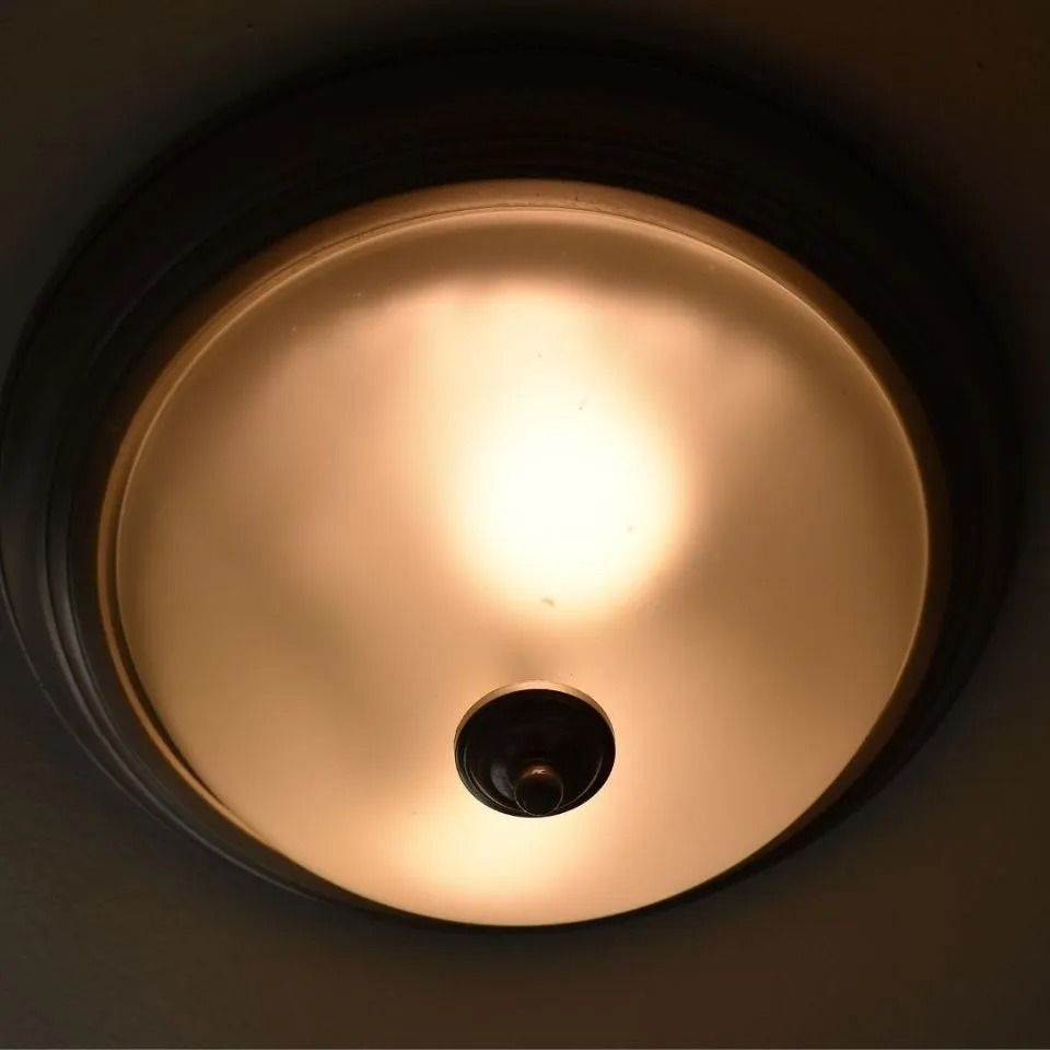 Lampada da soffitto con paralume rotondo in vetro smerigliato, che emana una luce calda.