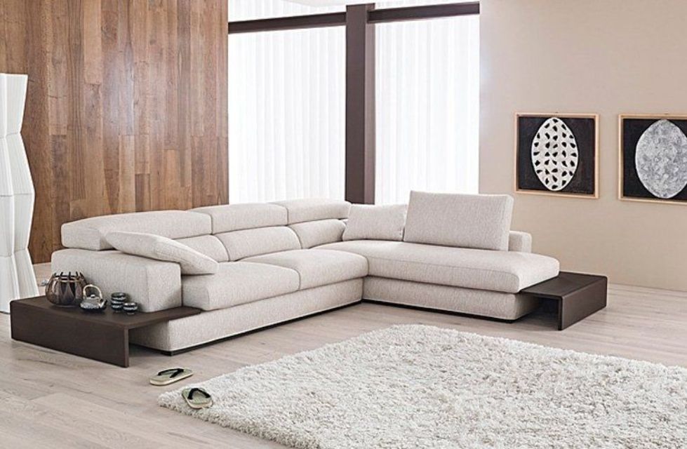 Un moderno divano componibile beige chiaro con tavolini laterali incorporati marrone scuro in un soggiorno contemporaneo.