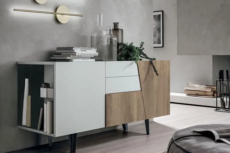 Credenza moderna con ripiano aperto, cassetti e dettagli in legno, decorata con decorazioni contro la parete grigia.
