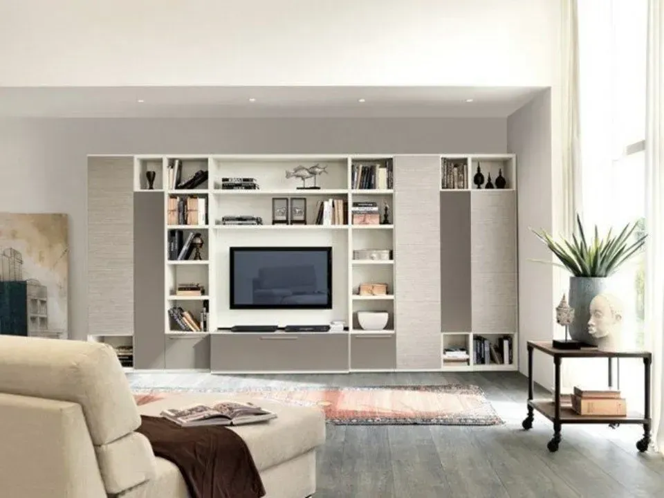 Soggiorno con centro di intrattenimento integrato, TV, scaffali con decorazioni, colori neutri, ampia finestra, divano.